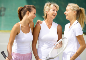 3 women on tennis tennis court holding their racquets